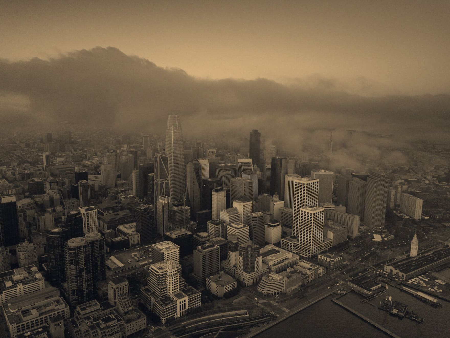 Aerial view of a city under rolling fog at dusk